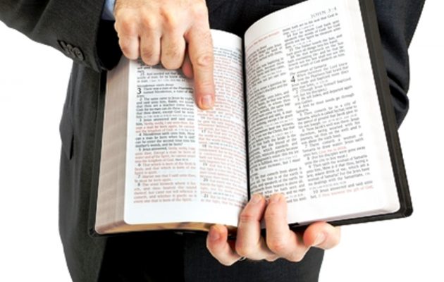 Businessman or minister holding a bible open to John 3:16.  White background.